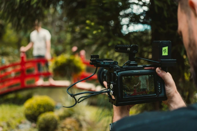 a man holding a camera in front of a red bridge